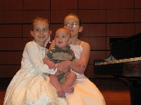 Two girls and small child on piano bench