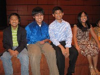 Four students sit on stage edge